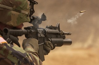 soldier firing bullet from rifle